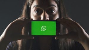 žena držící telefon s logem aplikace whatsapp