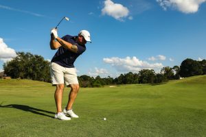 muž v černém tričku a bílých kraťasích hrající golf