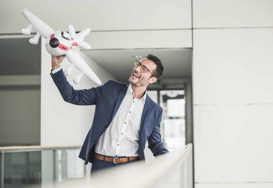 laughing businessman playing with toy aeroplane PR spiritmedia