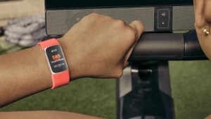 Chytrý náramek Fitbit Charge 6 s korálovým páskem na ruce uživatele