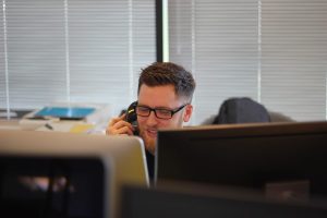 Telefonující muž za monitorem počítače