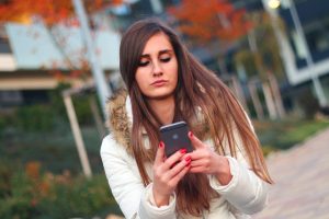 Žena píše textovou zprávu na chytrém telefonu Apple iPhone