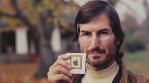 Steve Jobs držící v ruce kartičku se „starým“ logem společnosti Apple (ilustrační obrázek)