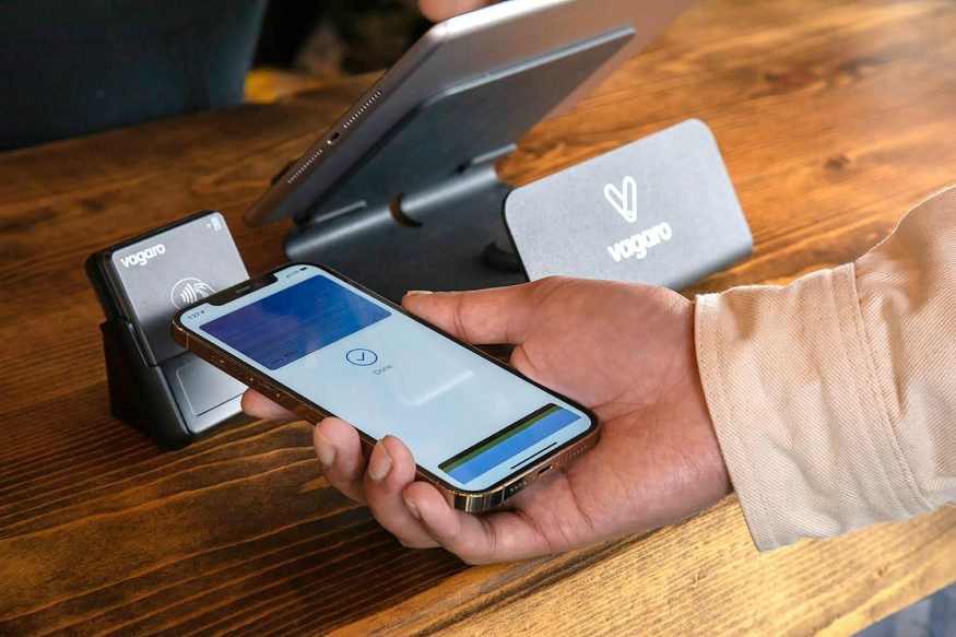 Člověk platící bezkontaktně skrze iPhone Člověk platící bezkontaktně skrze iPhone