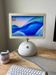 Počítač iMac G4 s operačním systémem macOS 26 a designovým jazykem Liquid Glass