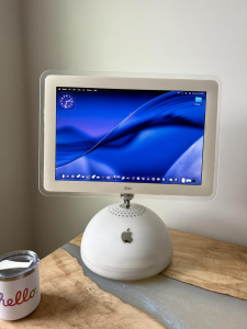 Počítač iMac G4 s operačním systémem macOS 26 a designovým jazykem Liquid Glass