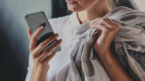 Žena držící chytrý telefon, který si podepírá malíčkem (ilustrační obrázek)