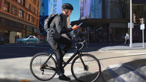 Cyklista ve městě s telefonem v ruce (ilustrační obrázek)