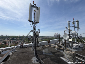 Anténní systémy mobilní sítě umístěné na střeše budovy s výhledem na Prahu