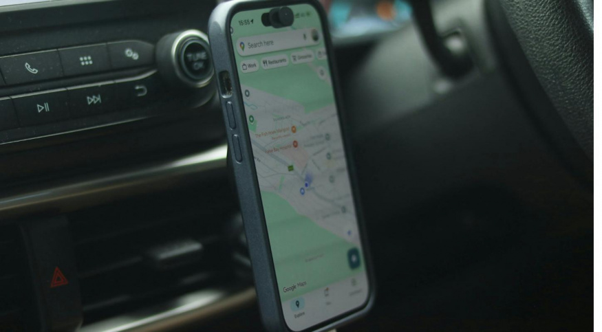 Smartphone v držáku na palubní desce auta s navigací Google Maps