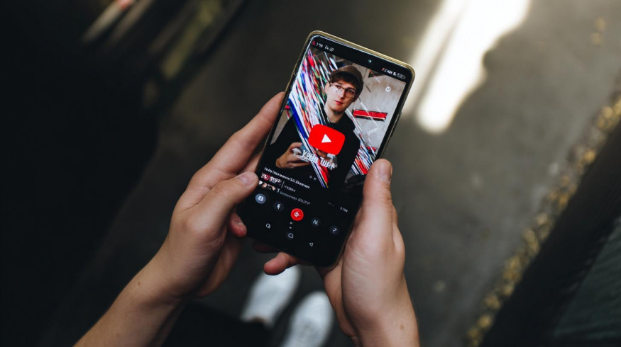 Mobilní aplikace YouTube na chytrém telefonu v rukou uživatele (ilustrační obrázek)