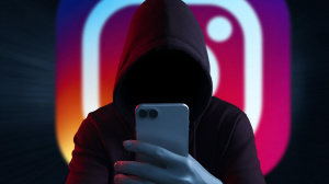 Hacker s chytrým telefonem, na pozadí logo Instagramu (ilustrační obrázek)