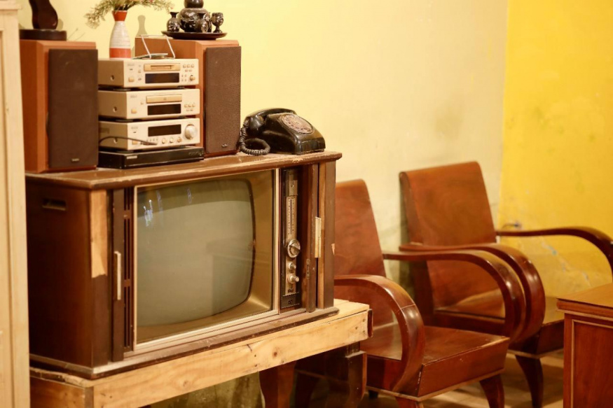 Starší obývací pokoj s retro televizí, telefonem a křesly