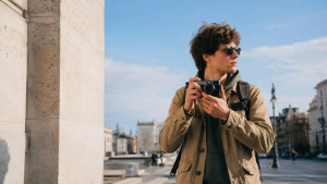 Fotograf s kompaktním fotoaparátem Muž fotografuje malým kompaktním fotoaparátem v ulici