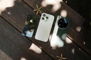 Tři smartphony na dřevěném stole Tři smartphony položené na tmavém dřevěném stole