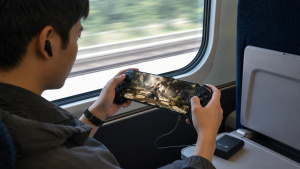 Hráč ve vlaku drží smartphone s připínacím ovladačem