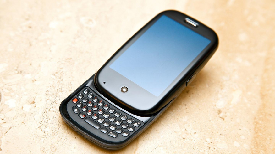 Palm Pre s vysunutou klávesnicí Otevřený Palm Pre s vysunutou fyzickou klávesnicí leží šikmo na světlém povrchu