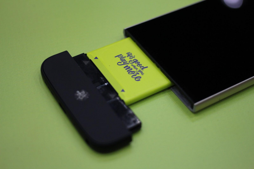LG G5 s vysunutým spodním modulem Telefon LG G5 s vytaženým spodním dílem a částečně vysunutou žlutou baterií