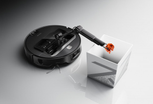 Roborock Saros Z70 s vyklopeným ramenem drží papírovou kouli nad úložným boxem