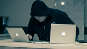 Muž v černé mikině pracuje se dvěma MacBooky