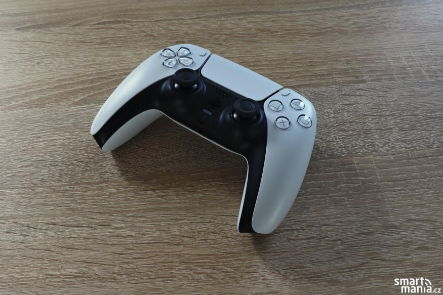 Ovladač DualSense a analogové páčky Bílý ovladač DualSense se dvěma černými analogovými páčkami na dřevěném stole