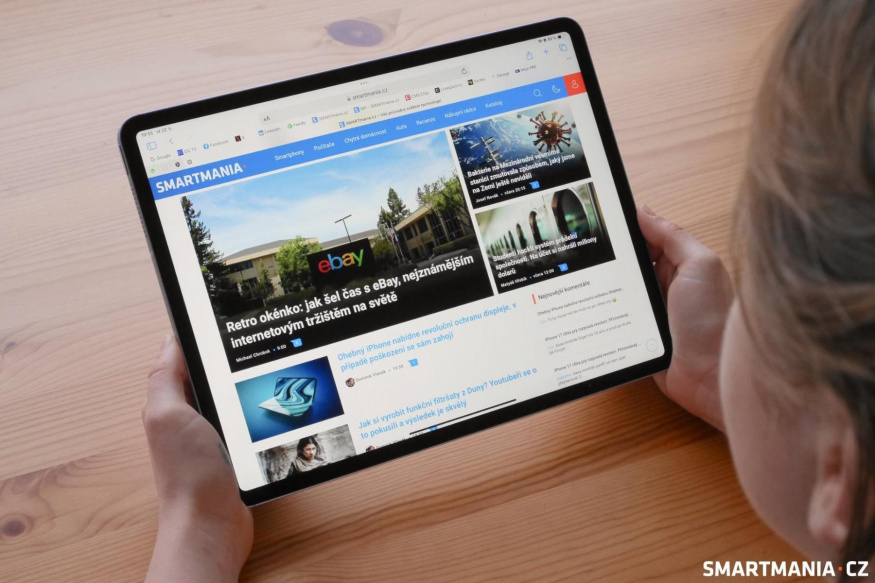 Čtení webu na iPadu Air 2024 Člověk drží iPad Air naležato nad stolem a prohlíží web SMARTmania.cz