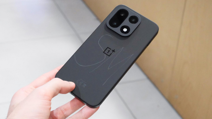 Černý OnePlus 15 v ruce Černý OnePlus 15 držený v ruce zezadu