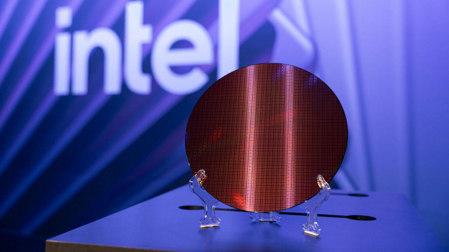 Wafer s čipy Intel Clearwater Forest Kulatý křemíkový wafer s opakující se strukturou čipů na průhledném stojánku