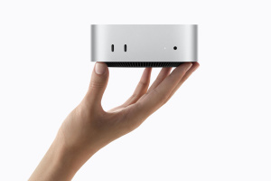 Stříbrný Mac mini M6 držený v dlani, s předními porty USB-C a sluchátkovým konektorem
