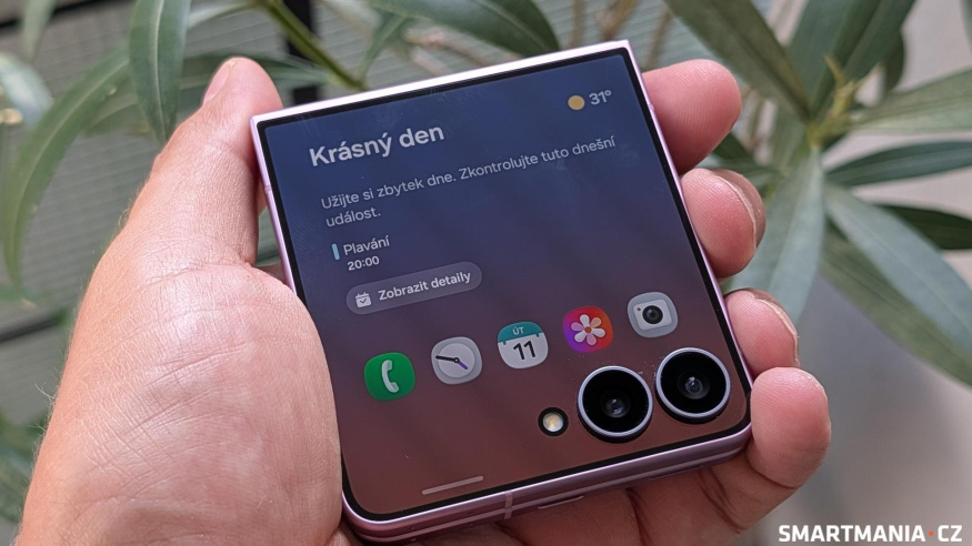 Zavřený Galaxy Z Flip8 v dlani Zavřený Galaxy Z Flip8 v ruce s počasím a událostí kalendáře na vnějším displeji