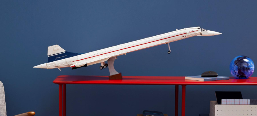 LEGO Concorde na výstavním stojanu Bílý LEGO Concorde s přídí zvednutou na stojanu na červené polici proti modré stěně