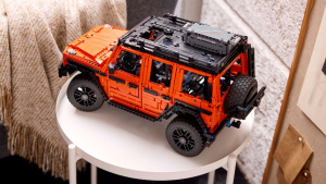 Oranžový LEGO Technic Mercedes G 500 na bílém kulatém stolku vedle šedého křesla