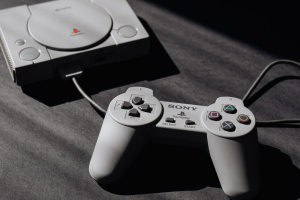 Původní Sony PlayStation s připojeným ovladačem na tmavé podložce