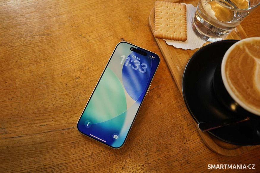iPhone 17 s rozsvíceným displejem na dřevěném stole vedle šálku kávy iPhone 17 s rozsvíceným displejem na dřevěném stole vedle šálku kávy