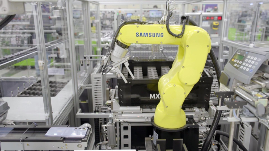 Robotická paže na lince pro Galaxy Z Fold 5 v továrně Samsungu v Gumi Žlutá robotická paže s nápisem Samsung u telefonu na výrobní lince