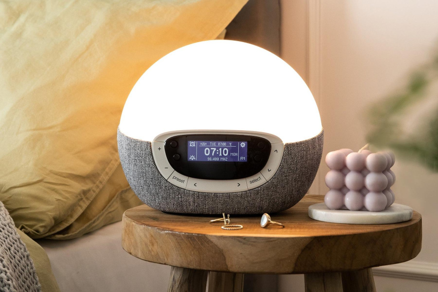 Lumie Bodyclock Shine 300 Rozsvícený Lumie Shine 300 na dřevěném stolku, s displejem a tlačítky kolem něj